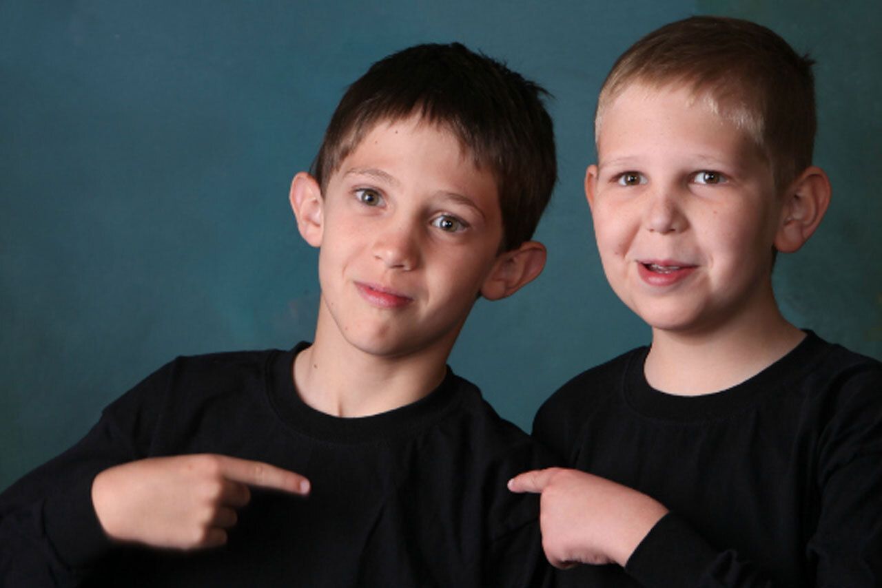 Two smiling boys pointing at each other